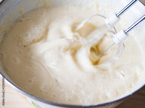 The mixer quickly stirs flour, milk and eggs for Russian pancakes. Close-up