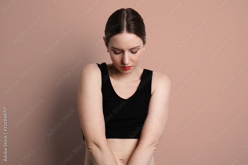 Fototapeta premium Young woman wearing casual black underwear looking down and posing in the studio. 