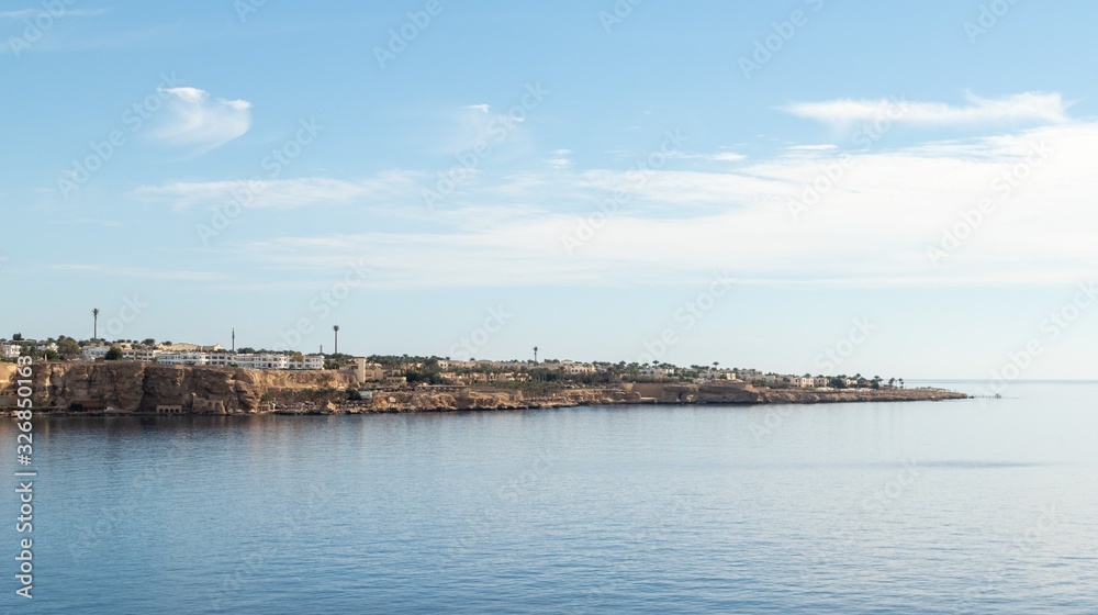 Egypt, Sharm El Sheikh, Seaside coast, palm trees, houses, buildings against the blue sky.