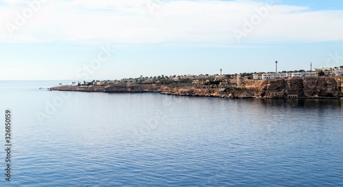 Egypt  Sharm El Sheikh  Seaside coast  palm trees  houses  buildings against the blue sky.