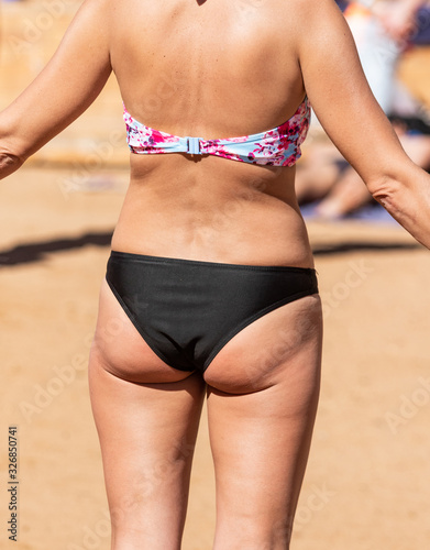 Girls on the sandy beach in swimming trunks, rear view of lingerie. photo