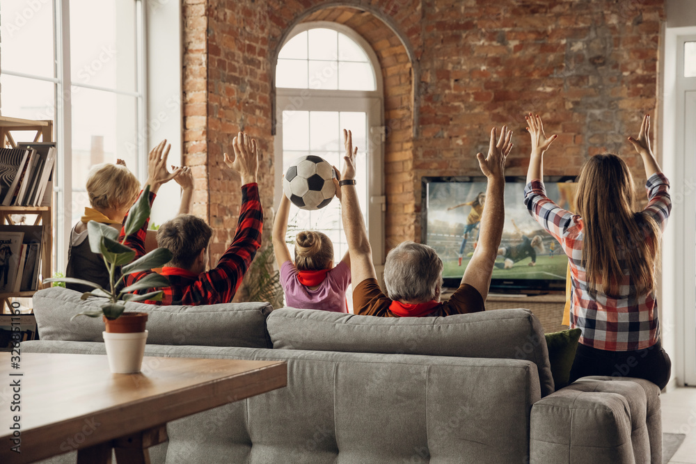 Victory. Excited, happy family watching soccer, football match, championship on the couch at home. Fans emotional cheering for favourite national team. Daughter, dad and grandpa. Sport, TV, having fun