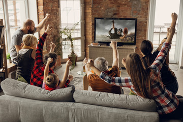 Victory. Excited, happy family watch american football match, championship on the couch at home. Fans emotional cheering for favourite national team. Daughter, dad and grandpa. Sport, TV, having fun.