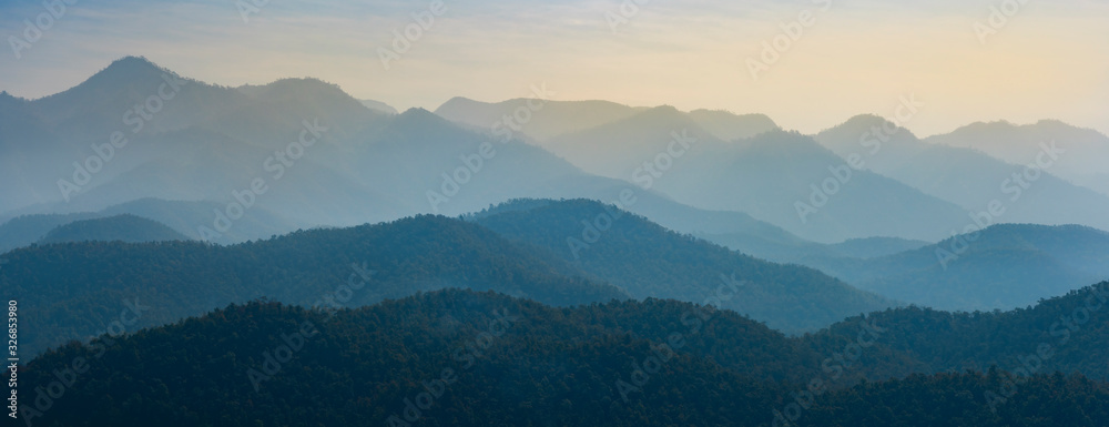 Amazing wild nature view of layer of mountain forest landscape with cloudy sky. Natural green scenery of cloud and mountain slopes background. Maehongson,Thailand. Panorama view.