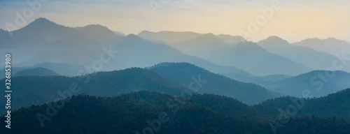 Obraz  z motywem Amazing wild nature view of layer of mountain forest landscape with cloudy sky. Natural green scenery of cloud and mountain slopes background. Maehongson,Thailand. Panorama view.