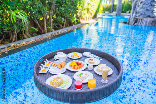 Floating breakfast set in tray with fried egg omelette sausage ham bread fruit milk juice coffee © siraphol
