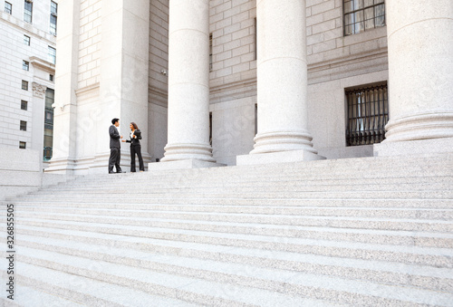 Two well dressed professionals in discussion on the exterior steps of a courthouse. Could be lawyers, business people etc. photo
