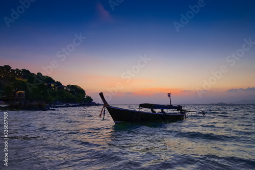 view seaside evening of a long-tail boat floating in the sea with sun shine and cloudy sky background, sunset at Lipe island, Satun, southern Thailand.