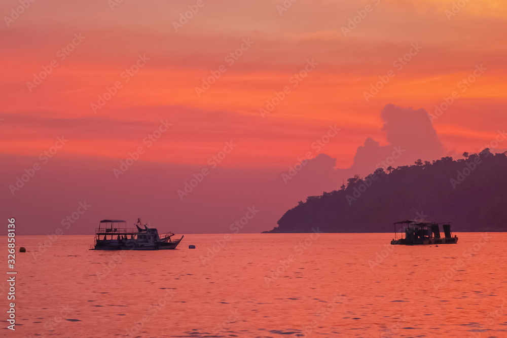 Sea view evening of the ships floating in the sea with island and red sky background, Twilight at Lipe island, Satun, southern Thailand.
