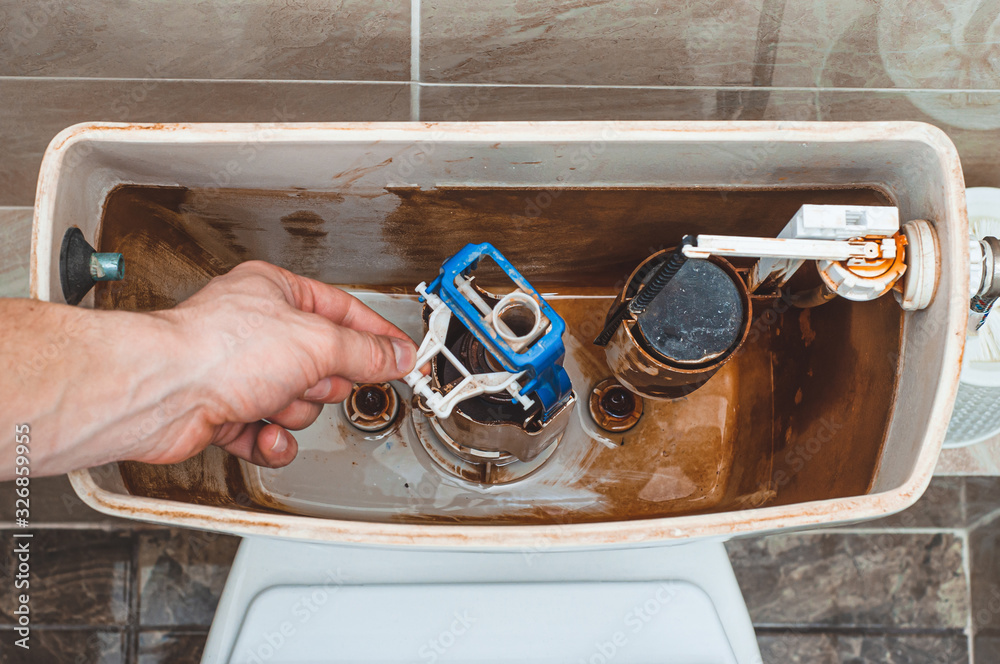 Unscrewing the fittings for draining the water in the toilet flush tank