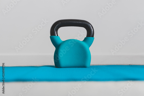 Fototapeta Naklejka Na Ścianę i Meble -  home gym concept, blue yoga mat with kettlebell shot at shallow depth of field from low perspective