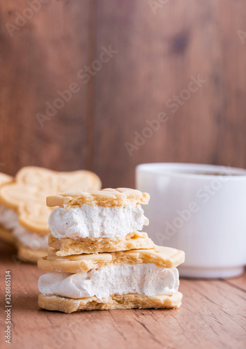 Shortbread cookies with meringue in the form of a flower, on a light wood background.