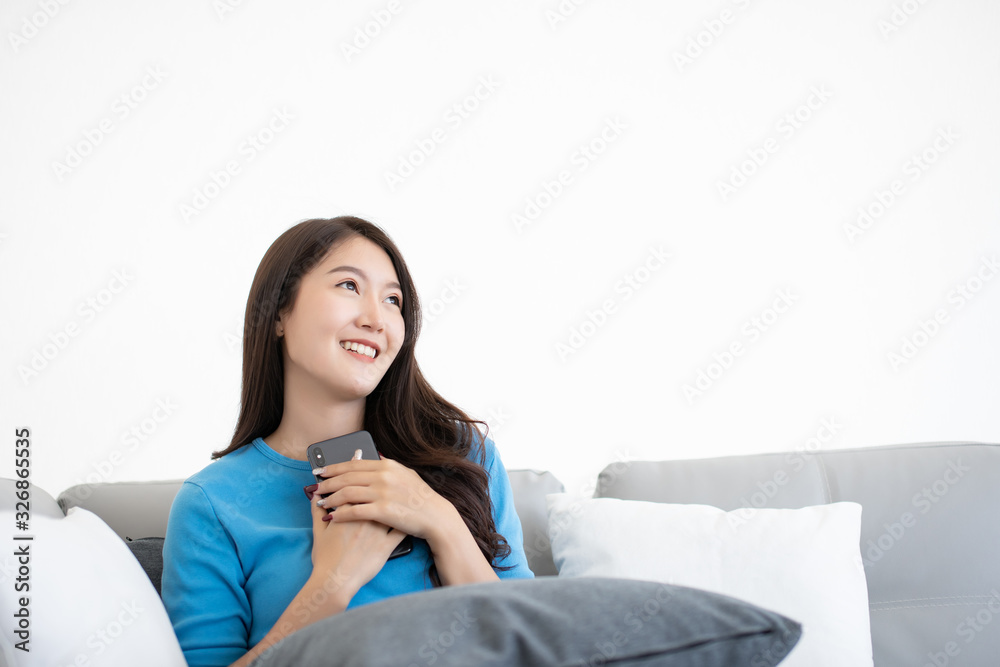 Portrait of happy smiling beautiful Asian woman siting in sofa imagine and looking something on copy space Portrait of happy smiling beautiful Asian woman siting in sofa imagine and looking something on copy space
