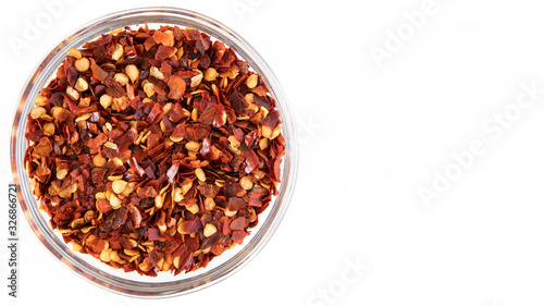 crushed red chili pepper in glass bowl. Top View on white background