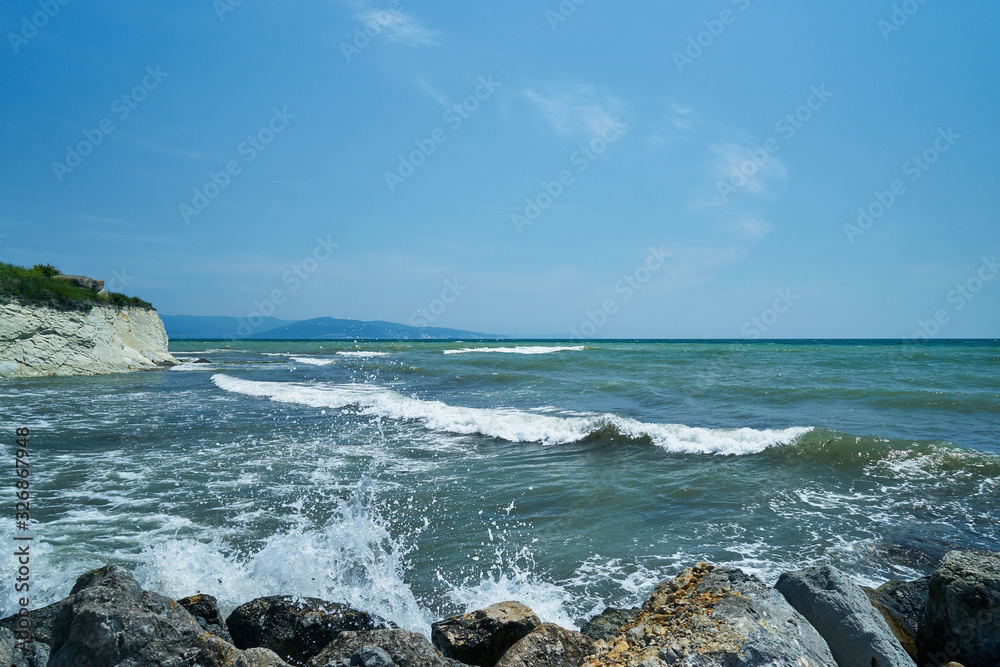 Image of the sea shore. The wave breaks on the stones.