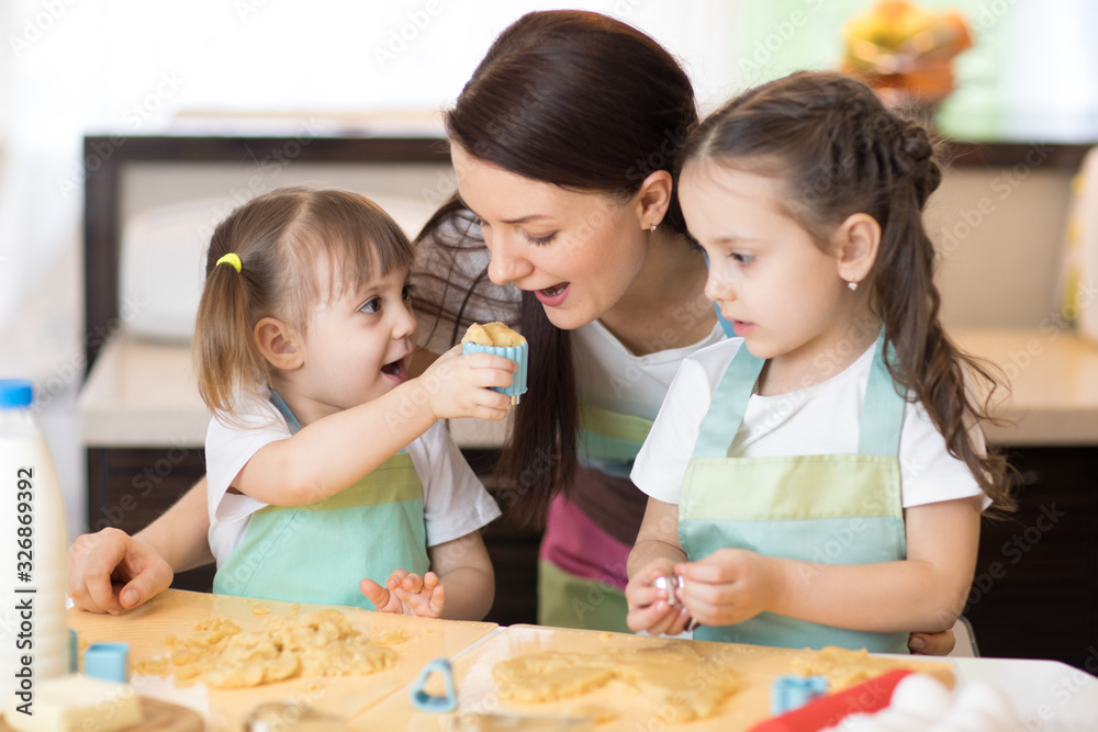 Fototapeta premium Mother and children weared aprons making together cookies