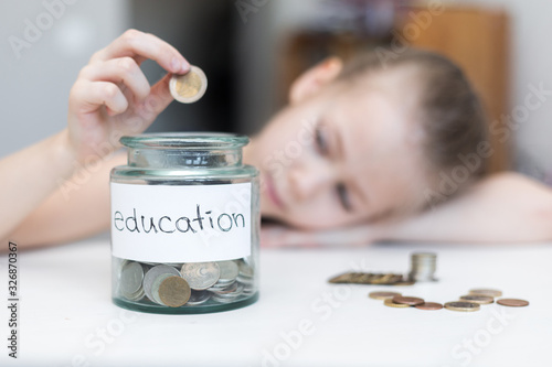 A little girl saves money for education. child counts and puts coins in a glass bottle in her room. The child saves money on the concept of the future