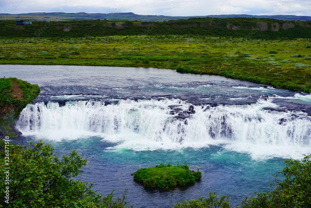a picturesque small waterfall with turquoise water on the expanses of Iceland, a summer cloudy day a picturesque small waterfall with turquoise water on the expanses of Iceland, a summer cloudy day