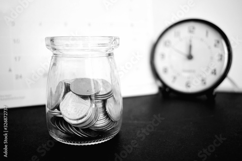 A clear glass bottle with a coin inside.  It is a black and white tone that is used for saving, needy finances or poverty.