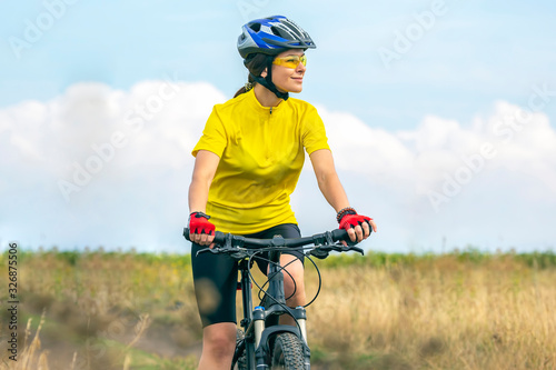 Fototapeta Naklejka Na Ścianę i Meble -  Beautiful girl in yellow riding a bike in nature. Sports and recreation. Hobbies and health.