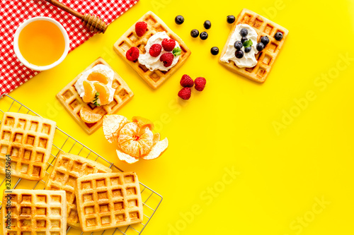Breakfast with freashly baked belgian waffles on yellow background top-down frame copy space photo