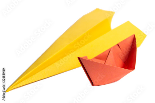 Red paper boat and yellow paper plane on an isolated white background