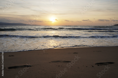 Golden dawn at sea  waves running onto the sand