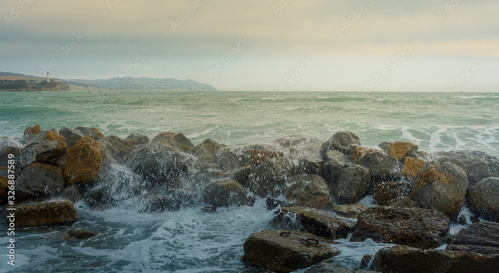 Raging waves crash against rocky shore in storm. Sea spray and foam Raging waves crash against rocky shore in storm. Sea spray and foam