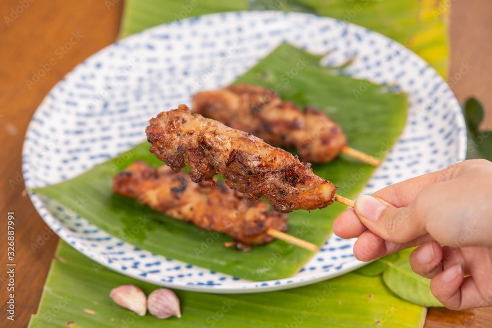 Grilled pork skewers put on the ground, green banana stump leaves