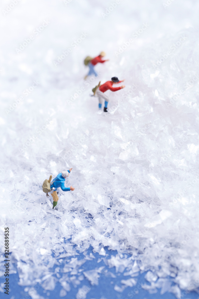 Miniature man climbing snow mountain