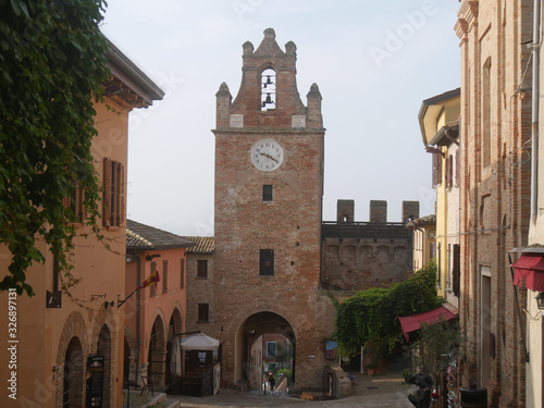 street in the historic center of the village of Gradara through buildings with the clock tower in the background