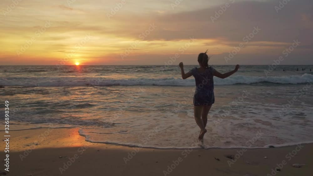 Silhouette of young happy and excited Asian woman at beautiful beach enjoying golden hour at tropical beach of Bali island in holiday travel destination concept Silhouette of young happy and excited Asian woman at beautiful beach enjoying golden hour at tropical beach of Bali island in holiday travel destination concept