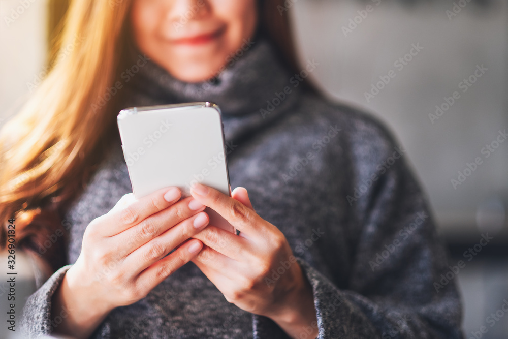 Closeup image of a beautiful woman holding and using mobile phone