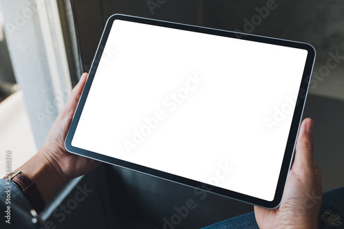 Mockup image of a woman holding black tablet pc with blank white screen in cafe photo