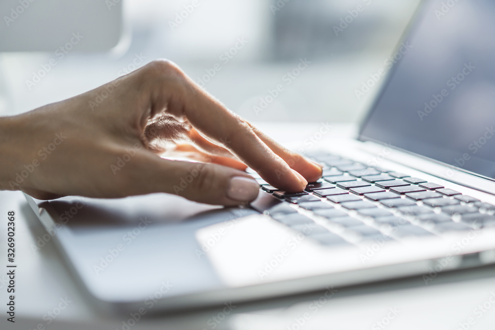 Female hands typing on laptop keyboard in sunny office, business and technology concept. Close up Female hands typing on laptop keyboard in sunny office, business and technology concept. Close up