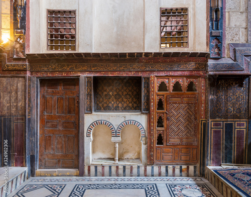 Wooden painted floral patterns, embedded arched niche, wooden door, wooden engraved cupboard, calligraphy decoration, and marble floor with geometric pattern at El Sehemy ottoman era historic house  photo