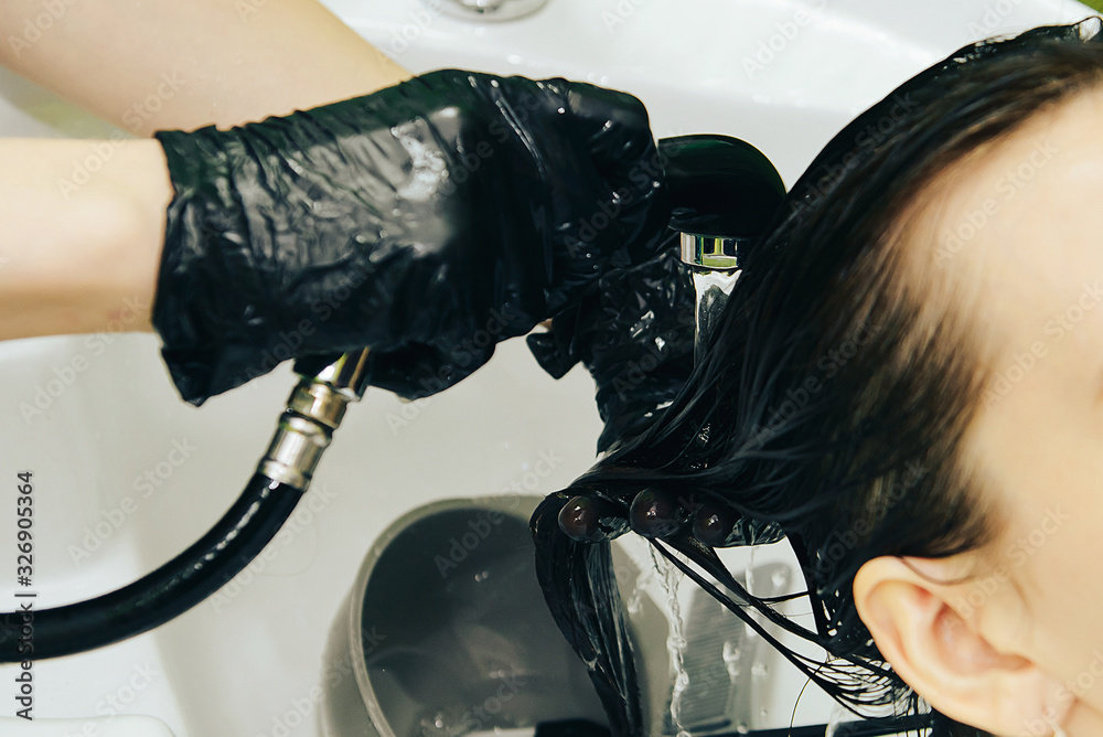 Fototapeta premium Close-up, a master Barber washes the head of a girl client.