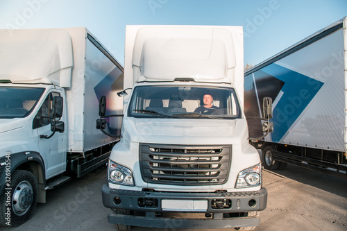 A man driver is sitting in the cab of a modern truck.