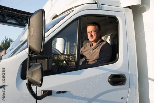 A man driver is sitting in the cab of a modern truck.