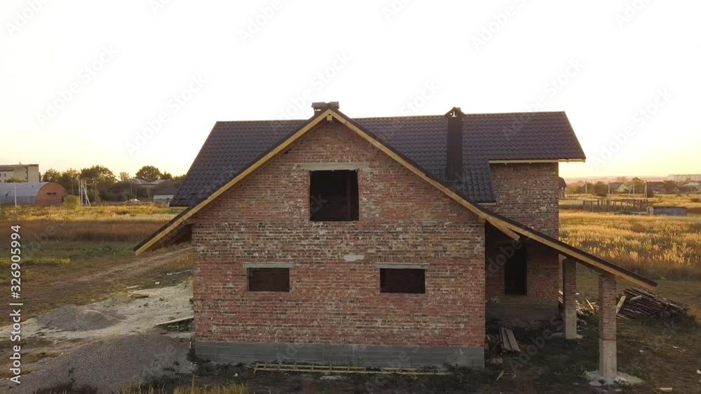 Aerial view of unfinished house with wooden roof structure covered with metal tile sheets under construction. Aerial view of unfinished house with wooden roof structure covered with metal tile sheets under construction.