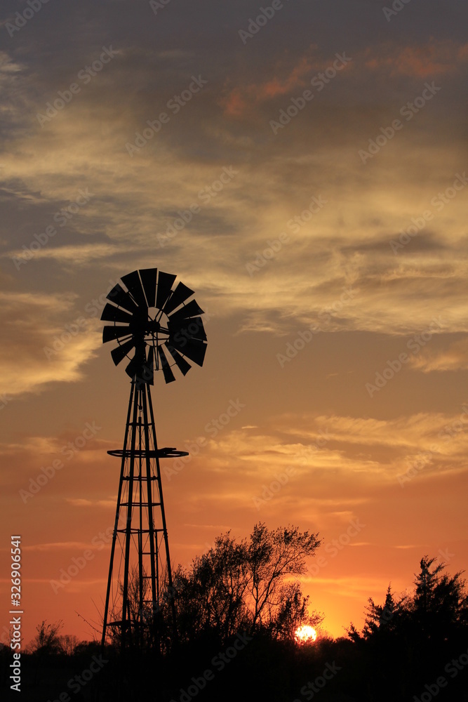 windmill at sunset with a colorful sky and tree's in Kansas. windmill at sunset with a colorful sky and tree's in Kansas.