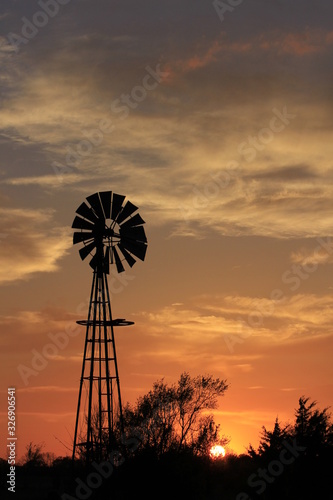 windmill at sunset with a colorful sky and tree's in Kansas.