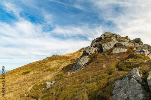 mountain top lonely rocky stone peak highland scenic view with blue sky white clouds background