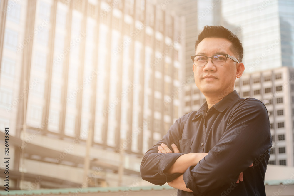 Confident male business executive with arms crossed standing in front of office building Confident male business executive with arms crossed standing in front of office building