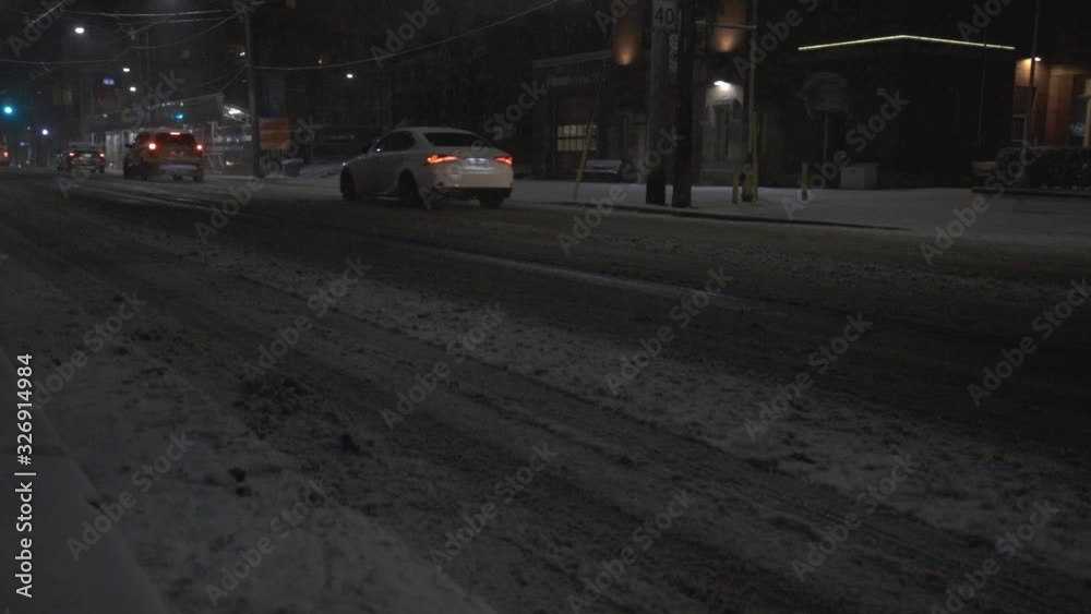 Car passing by the road covered with thick snow on a dark winter night in Canada - medium shot Car passing by the road covered with thick snow on a dark winter night in Canada - medium shot