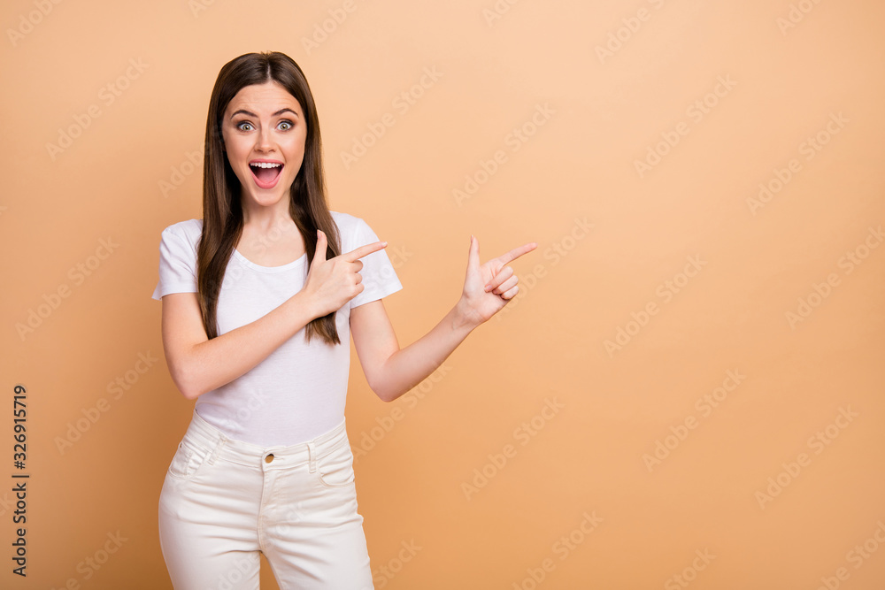 Astonished excited girl point index finger copyspace direct way notice incredible ads demonstrate display promotion impressed scream omg wear trendy trousers isolated beige color background Astonished excited girl point index finger copyspace direct way notice incredible ads demonstrate display promotion impressed scream omg wear trendy trousers isolated beige color background
