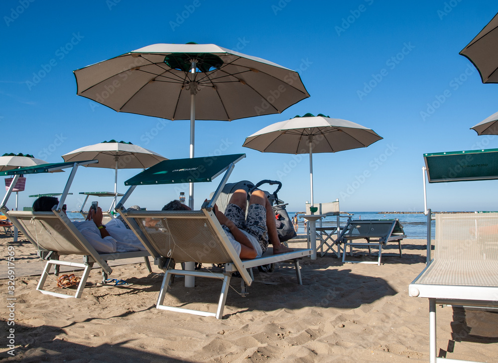  People are resting on a sunny day at the beach in Cesenatico, Italy