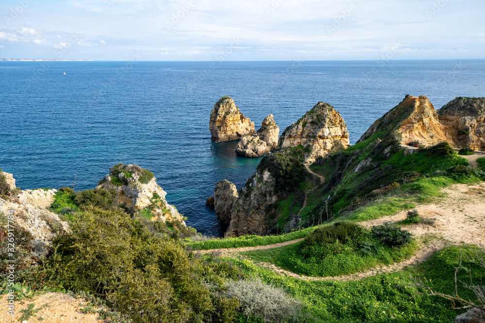 Scenic natural cliff formations of Algarve coastline with green grass at Ponta da Piedade, in Algarve Portugal
