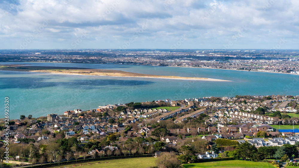 View over Dublin city from the top of the Shielmartin Hill on a sunny spring day in Howth, Ireland. Seaside town landscape.