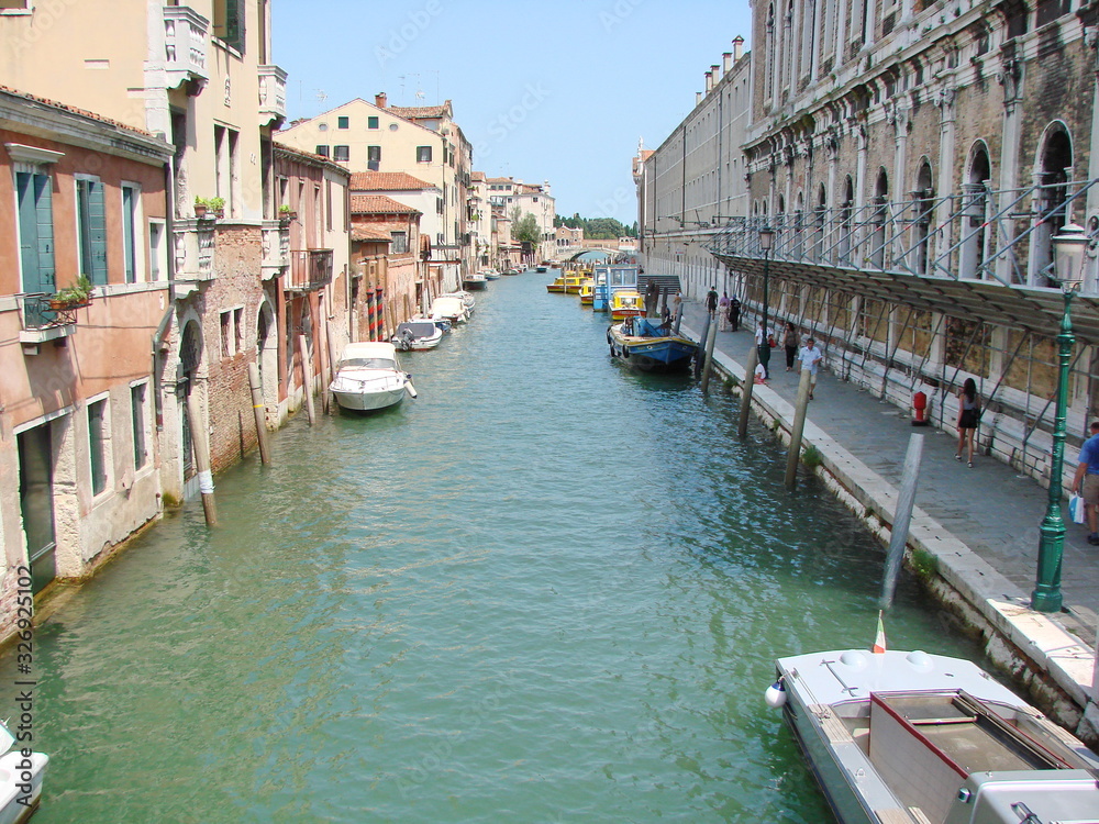 The unique landscape of the narrow waterways of sunny Venice, connected by small numerous bridges.